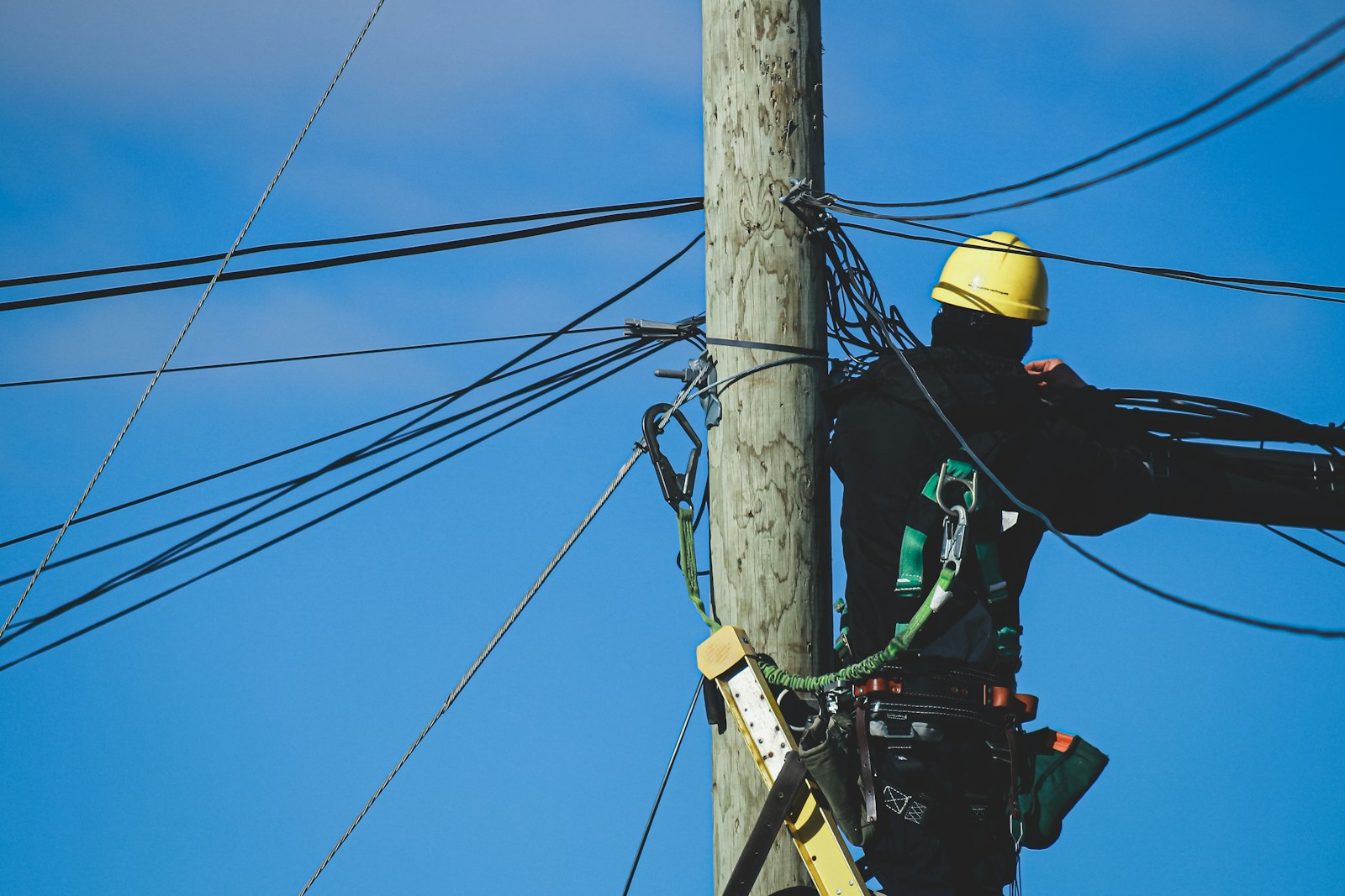 Servicios Asenov Telecomunicaciones Cox - man in black jacket and yellow helmet on brown wooden post under blue sky during daytime